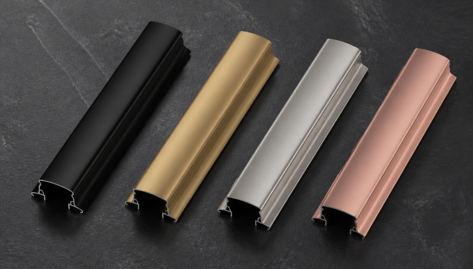 Four aluminium profile handle finish samples on dark stone — matte black, champagne gold, brushed anodised silver and rose gold