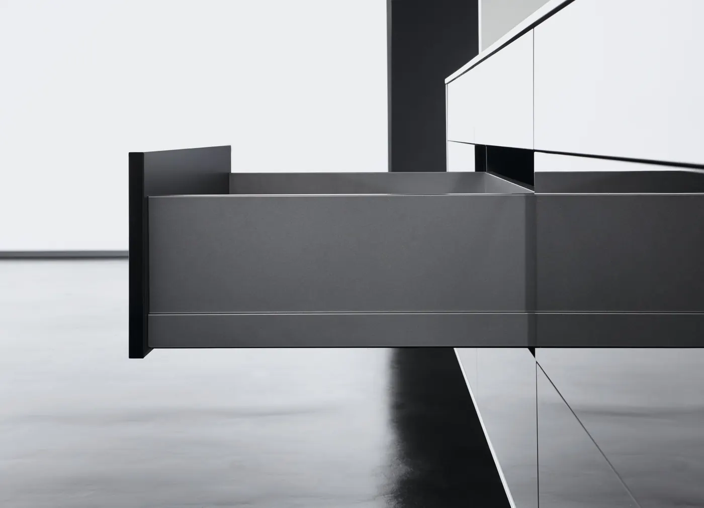 Side view of a tall grey metal drawer side pulled out of a gloss black kitchen run